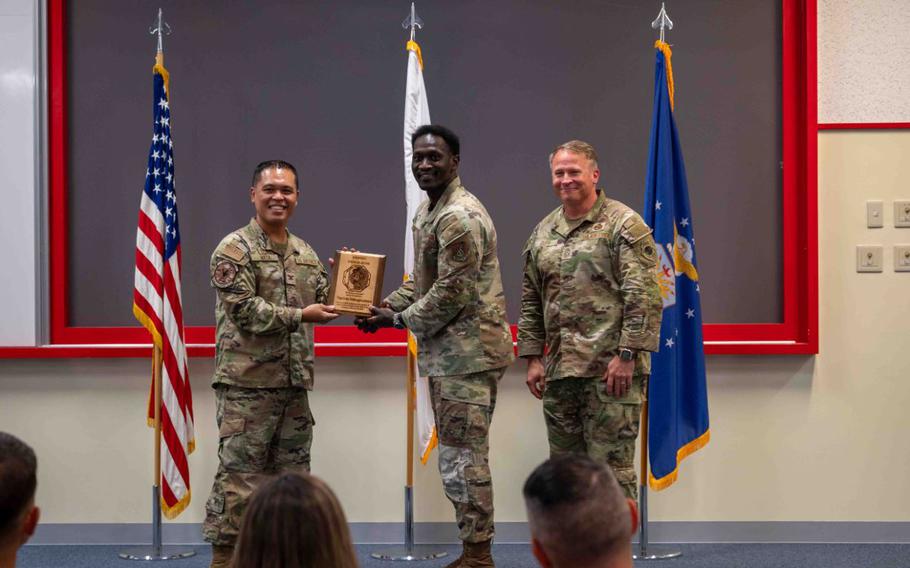 U.S. Air Force Col. Robinson Mata, 18th Mission Support Group commander, left, U.S. Air Force Tech. Sgt. Eddy Odongpinyokene, middle, 18th Maintenance Squadron non-commissioned officer in charge of development and instructions, and U.S. Air Force Chief Master Sgt. William Cupp, 18th Wing command chief, pose for a photo at the Erwin PME Center on Kadena Air Base.